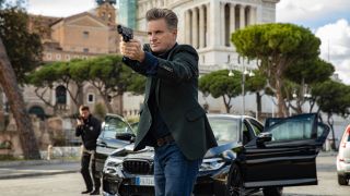 Shea Whigham pointing gun outside near a car with all its doors open in Mission: Impossible - Dead Reckoning