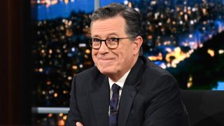 Stephen Colbert biting his lip trying not to laugh while interviewing Chris Hemsworth on The Late Show